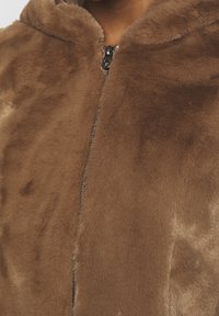 Brown faux fur zip-up jacket with a hood, featuring a smooth, soft texture and a glossy zipper detail at the neckline.