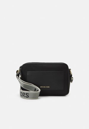 Sac bandoulière rectangulaire noir Michael Kors avec poche avant et large sangle grise affichant un texte de logo noir.