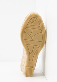 Semelle de sandale compensée, fabriquée en paille et en caoutchouc. Motif texturé sur la semelle avec une couleur beige clair. Taille marquée 37, étiqueté "Fabriqué en Espagne."