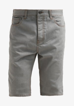 Lila T-Shirt mit dem Aufdruck "Organic Pineapples Florida", kombiniert mit grauen Shorts mit aufgerolltem Saum und grauen Sneakers.