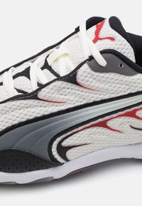 White mesh running shoe with red and black accents, featuring a padded collar, laces, and a textured sole for grip.