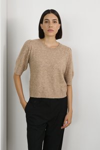 Beige kortærmet sweater med rund halsudskæring og struktureret strik. Bæres med sorte bukser med sidelommer og knapdetalje.