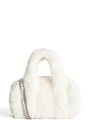 Bijela torba od umjetnog krzna sa zaobljenim oblikom, koja ima dva kratka ručka i srebrni lanac kao naglasak sa strane. Mekana tekstura kroz cijelu torbu.