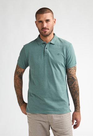 Turquoise poloshirt met kraag, drie knopen en een logodetail. Korte mouwen met een ontspannen pasvorm en een gladde stoftextuur.