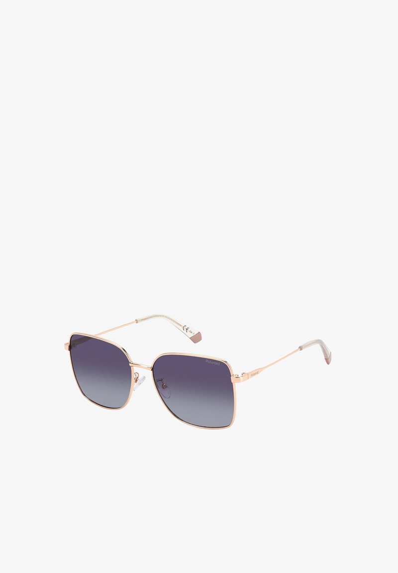 Lunettes de soleil carrées avec une fine monture en métal rose doré et des verres dégradés gris foncé sur fond blanc.