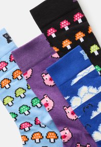Quatre chaussettes colorées avec des motifs pixelisés : bleue avec des champignons, violette avec des cochons, noire avec des champignons, et bleue avec des nuages et des chauves-souris.