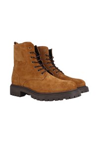 Botas de ante marrón hasta el tobillo con seis ojetes, cordones marrón oscuro y suelas de goma texturizadas que presentan un patrón de banda de rodadura resistente.
