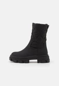Schwarze Knöchel-Ankle Boots mit einem gesteppte Stoffobermaterial, strukturiertem Sohlen und einer klobigen Plattform. Verfügt über eine Schlaufe an der Rückseite für ein einfaches Anziehen.