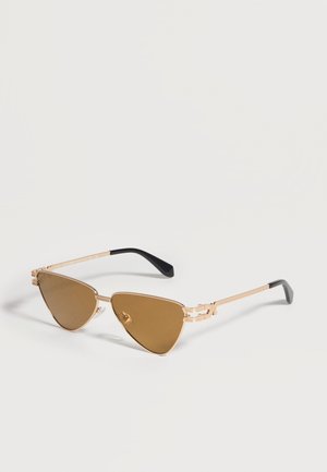 Lunettes de soleil œil-de-chat à monture métallique dorée avec verres teintés marron et branches aux embouts recouverts de plastique noir sur fond blanc.