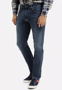 Ciemnoniebieskie dżinsy o slim fit, pięciokomorowym designie, widocznym przeszyciu, zestawione z granatowymi trampkami z czerwonymi akcentami.