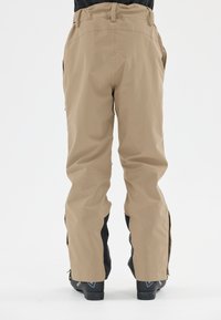 Pantalon de neige beige avec une texture lisse, présentant des ventilations latérales zippées et des accents noirs au niveau des poignets. Conçu pour les activités de plein air.