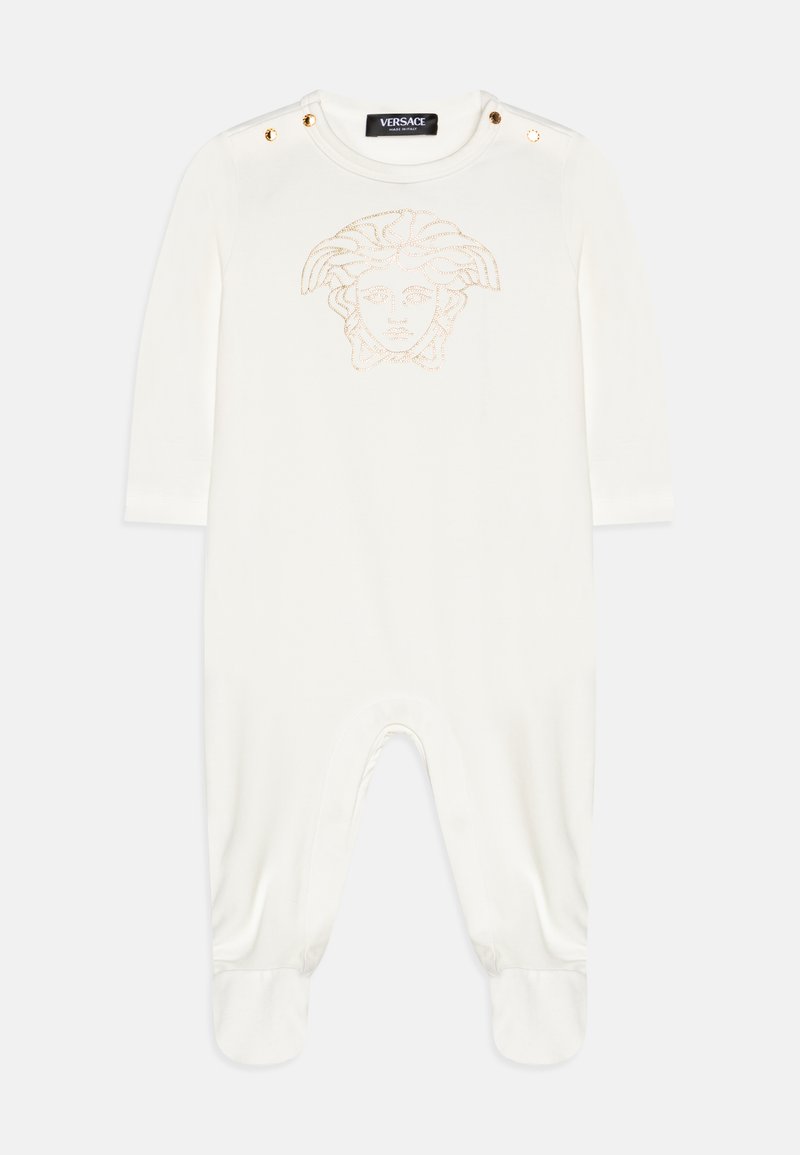 White onesie made of soft fabric featuring a Medusa logo in gold stitching, snap button accents on shoulders, and footed design.