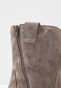 Grijze suède enkelboot met een zijrits en een flap. Heeft een gladde textuur en strakke lijnen voor een gestroomlijnde uitstraling.