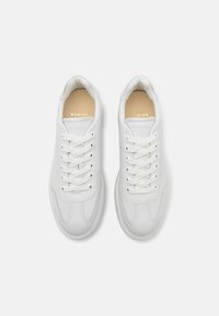 Hvite lær sneakers med rund tå, polstret krage, flate hvite snører og subtile sømdetaljer. Gull merkevarelogo på beige innersåle.
