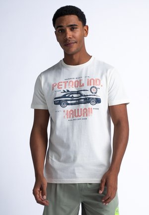 Lichtbeige t-shirt gemaakt van katoen, met een grafisch ontwerp van een auto en de tekst "PETROL IND. HAWAII" in sterke kleuren. Korte mouwen, ronde hals.