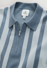 Grau und hellblau gestreiftes Strick-Polo mit Reißverschlusskragen, das eine glatte Textur und einen dezenten Glanz aufweist. Größenetikett sichtbar.