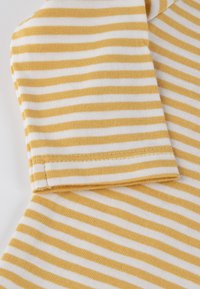 Gestreifter Stoff mit abwechselnden gelben und weißen horizontalen Linien, einer weichen Textur und einem sauber genähten Manschettendetail.