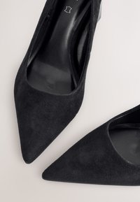 Crne salonke od antilopa s visokim potpeticama, šiljastim vrhovima i glatkom unutrašnjom postavom. Diskretna tekstura i elegantan dizajn u cijelosti.