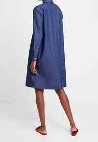 Jeansklänning i mörkblått, med knappad krage, långa ärmar, knälång med fickor, slät textur, avslappnad passform, platt bak.