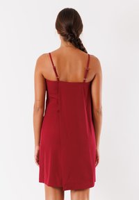 Abito rosso senza maniche con spalline regolabili. Tessuto liscio; vestibilità dritta con dettaglio della cucitura posteriore. Design semplice ed elegante.