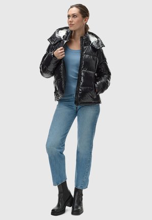 Black puffer jacket with a glossy finish, hood, and zip closure, worn over a blue ribbed top and light blue jeans, paired with black ankle boots.