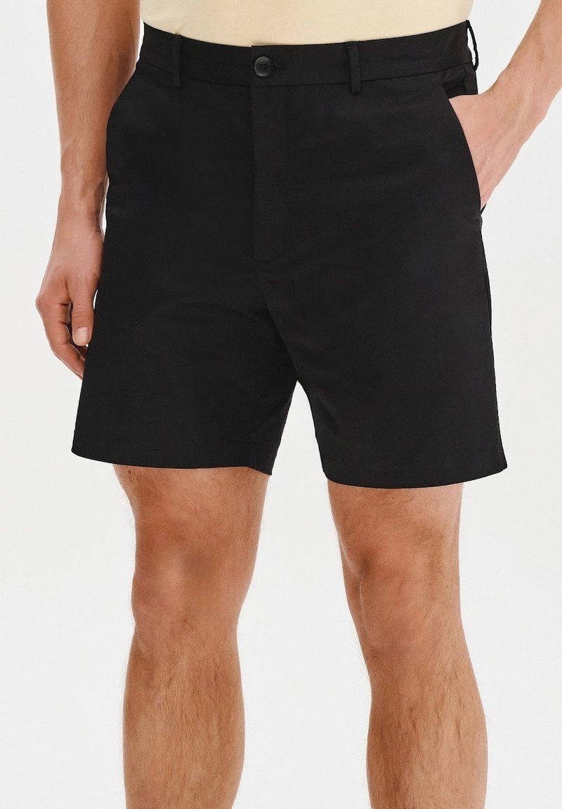 Czarne szorty wykonane z gładkiego materiału, z zapięciem na guzik, kieszeniami z przodu i prostym krojem, kończącym się powyżej kolana.