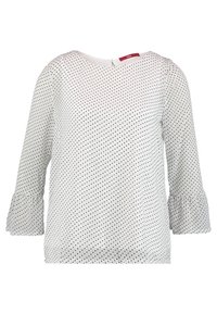 Blouse blanche à pois noirs, manches trois-quarts avec poignets volantés et encolure ronde avec petite fermeture à bouton dans le dos.