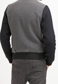 Grijze trui met donkerblauwe mouwen, gemaakt van een wolmix, met ribbels aan de onderkant en nette naden. Lichtjes cropped ontwerp, met minimale details.