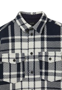 Camicia a quadri blu navy e bianca realizzata in tessuto testurizzato, con chiusura a bottoni, due tasche sul petto e un classico design del colletto.