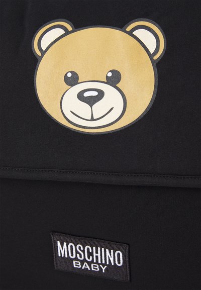 Black fabric featuring a cartoon bear face in beige with black accents and white highlights; includes a "Moschino Baby" label in white on a black background.