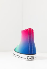 Baskets Converse montantes avec un design en dégradé passant du rose au bleu, avec des coutures blanches et une semelle en caoutchouc noire.