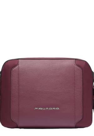 Compact rechthoekige donkerrode leren crossbodytas met afgeronde hoeken en zilveren Piquadro-logo in het midden aan de voorkant.