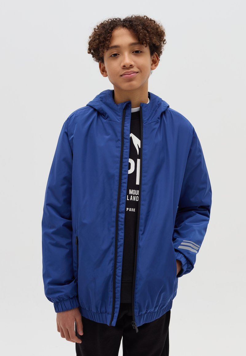 Blaues Kapuzenbomberjacke mit durchgehendem Reißverschluss, elastischen Bündchen und Seitentaschen. Glattes Material mit reflektierenden Streifen auf den Ärmeln.