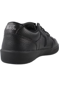 Sneaker en cuir noir avec surface texturée, bout rond et profil bas. Caractéristiques du logo classique sur le talon et semelle en caoutchouc plate.