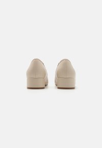 Beżowe skórzane buty na niskim słupku, okrągłym noskiem oraz detalami przeszycia wzdłuż szwów. Gładka tekstura i minimalistyczny design.