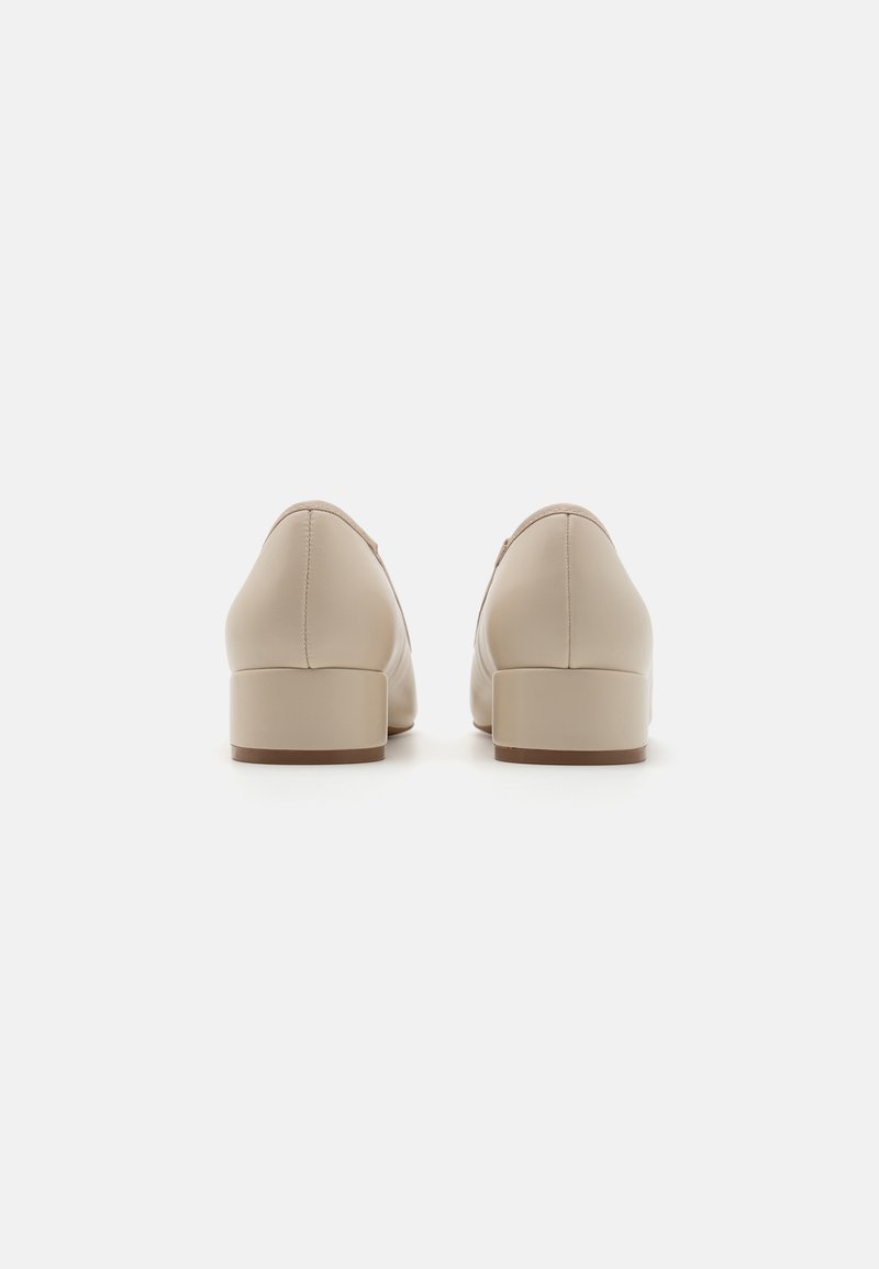 Chaussures en cuir beige avec un petit talon carré, bout arrondi et couture le long des coutures. Texture lisse et design minimaliste.