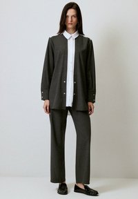 Tumehall oversized särgid valge krae ja nööpidega, sobivad hallid püksid. Mustad lamejalatsid dekoratiivsete elementidega.