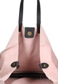 Roze suede schoudertas met zwarte leren handvatten. Beschikt over een messing drukknoopsluiting en een zachte binnenvoering. Open ontwerp voor gemakkelijke toegang.