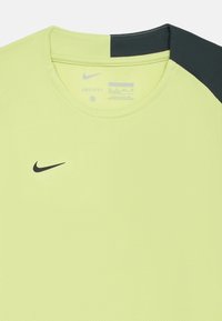 Tričko Nike DRI-FIT v žiarivej žltej farbe s textúrovaným povrchom a čiernymi akcentmi na pleciach. Krúžkový výstrih a logo na hrudi.