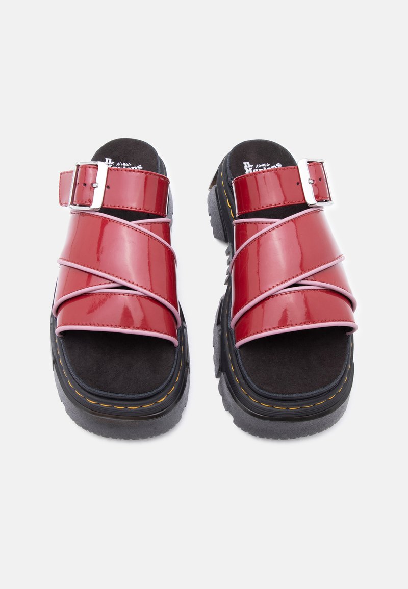 Sandali in pelle verniciata rossa con plantari imbottiti neri, suole spesse nere, cuciture gialle e fibbie argento regolabili sulle fasce.