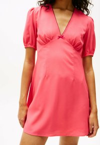 Vestido corto de satén rosa con escote en V, mangas abullonadas y un lazo debajo del escote, que presenta un cuerpo ajustado y una falda acampanada.