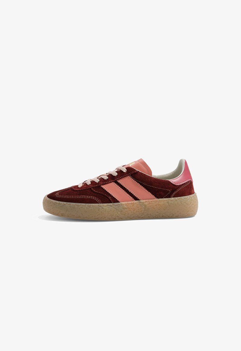 Basket profil bas en daim bordeaux, bandes en cuir rose et languette talon, lacets blancs, semelle en caoutchouc marron clair texturée.