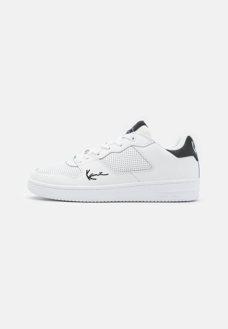 Hvide lædersneakers med perforerede sider, sorte detaljer på hælen og tungen samt et signaturlogo på siden. Gummisål.