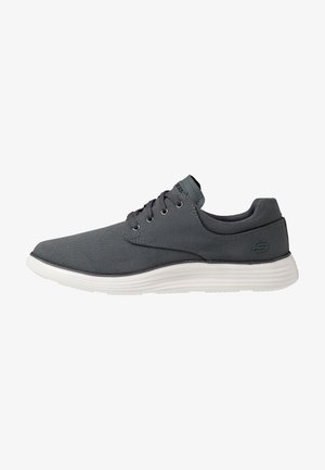 Ciemnoszary sneaker na sznurowadła z białą podeszwą, cholewką z siateczkowego materiału i zaokrąglonym noskiem, widziany z boku.