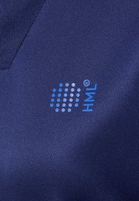 Gros plan d'un tissu bleu marine avec un logo à motif de points bleus et les lettres « HML » imprimées en bleu à la surface.