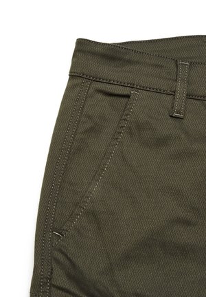 Olivgrüner, strukturierter Stoffhose mit einem enganliegenden Taillenbund, Gürtelschlaufen und einer Seiten Tasche mit kontrastierenden Nähdetails.