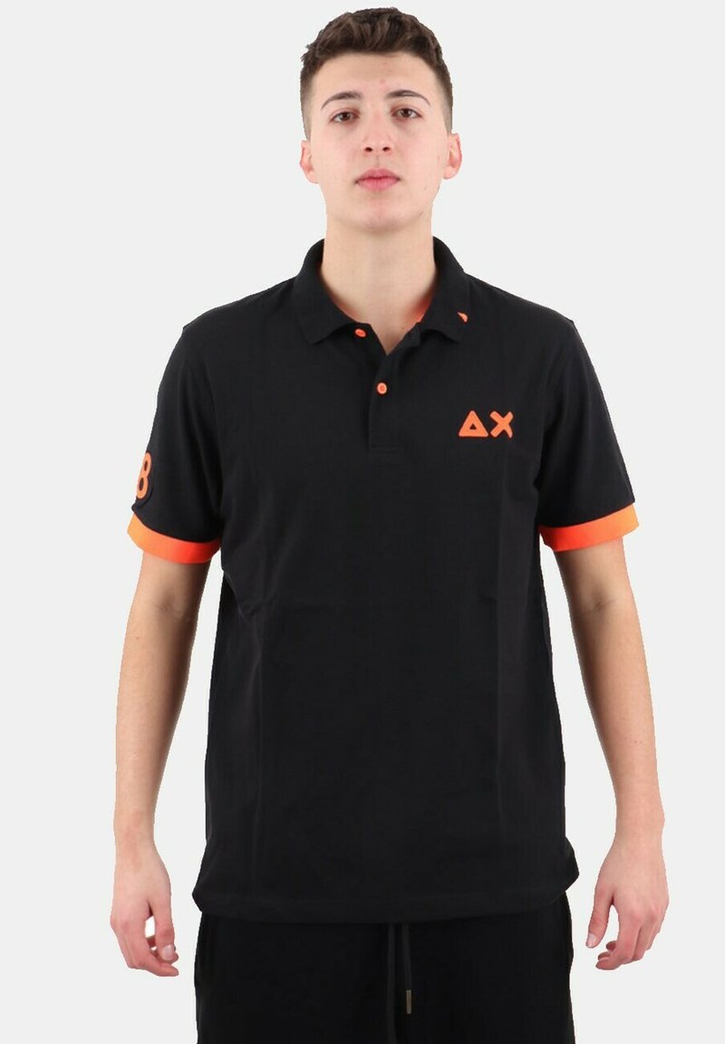 Polo nero con colletto, dettagli arancioni sulle maniche e logo. Realizzato in cotone con una texture liscia e una vestibilità comoda.