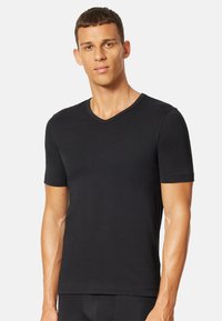 Sort kortærmet V-hals t-shirt lavet af glat bomuld, med et tætsiddende design og diskret syning langs halsudskæringen.