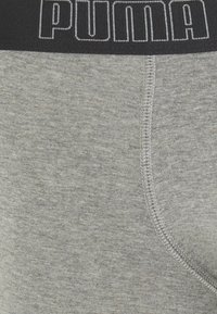 Graue Baumwoll-Boxershorts mit einem schwarzen elastischen Bund, auf dem das "PUMA"-Logo prangt, genähten Nähten und einer glatten Textur.