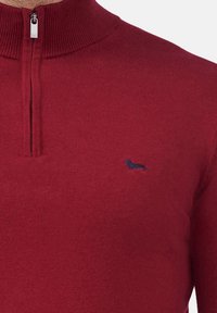 Pullover rosso con colletto alto, caratterizzato da una mezza cerniera. Piccola silhouette di un cane navy sul lato sinistro del petto. Materiale morbido e lavorato a maglia.